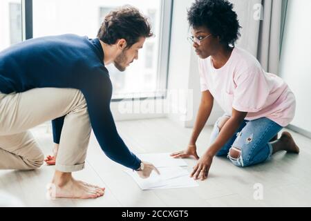 Afrikanische und Kaukasische gemischten Rennen Ehepaar auf dem Boden zu Hause unbezahlte Rechnungen prüfen, Steuern, Schulden, Bank Account Balance sitzen. Es ist ein Stockfoto