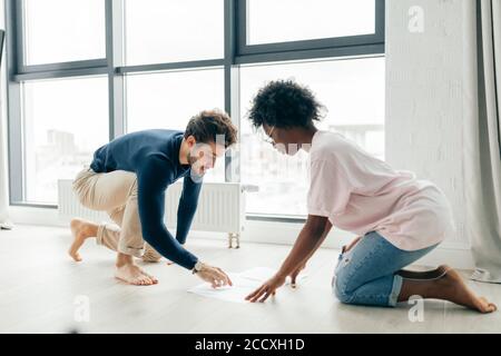 Afrikanische und Kaukasische gemischten Rennen Ehepaar auf dem Boden zu Hause unbezahlte Rechnungen prüfen, Steuern, Schulden, Bank Account Balance sitzen. Es ist ein Stockfoto