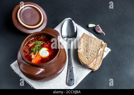 Borscht in einen Topf. Gemüsesuppe mit Fleisch, Sauerrahm und Knoblauch auf dunklem Grund. Traditionelle slawische Küche.Nahaufnahme.selektiver Fokus. Copyspace Stockfoto