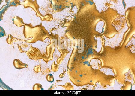 Goldene Tinte Tropfen auf weißem Papier Hintergrund. Stockfoto