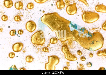 Goldene Tinte Tropfen auf weißem Papier Hintergrund. Stockfoto