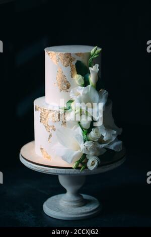 Zwei-klassen-Kuchen mit Blumen auf einem Stand aus Holz auf einem schwarzen Hintergrund. Stockfoto