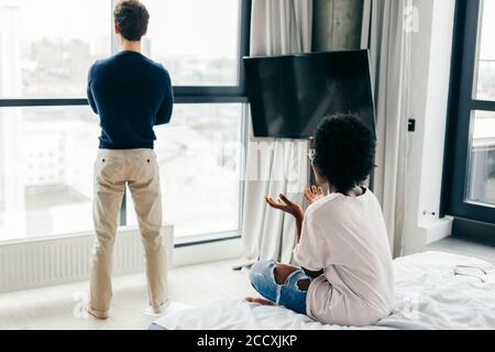 Frustrierte afrikanische Frau, die sich beleidigt und niedergeschlagen fühlt, nachdem sie wusste, dass die Verlobung gescheitert ist. Ihr anmutender Bräutigam von europäischem Aussehen gerecht Stockfoto