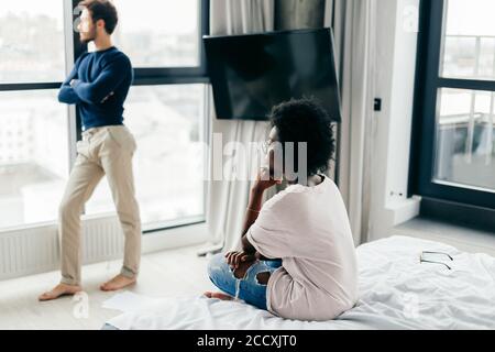 Frustrierte afrikanische Frau, die sich beleidigt und niedergeschlagen fühlt, nachdem sie wusste, dass die Verlobung gescheitert ist. Ihr anmutender Bräutigam von europäischem Aussehen gerecht Stockfoto