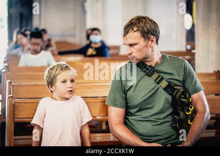 Christian Papa erzählt seinem Sohn biblische Geschichten über Jesus in kirk sitzen. Glaube, Religionsunterricht, moderne Kirche, Vatertag, väterliche Stockfoto