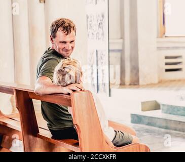 Christian Papa erzählt seinem Sohn biblische Geschichten über Jesus in kirk sitzen. Glaube, Religionsunterricht, moderne Kirche, Vatertag, väterliche Stockfoto