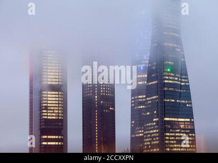 Cuatro Torres Business Area Bürogebäude im Abendnebel beleuchtet, Madrid, Spanien Stockfoto