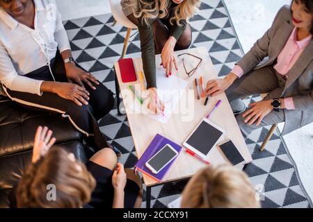 Multirassischen weibliche Mitarbeiter sitzen gemeinsam am Tisch, in Zusammenarbeit. Brainstorming Planung Sitzung Konzept. Stockfoto