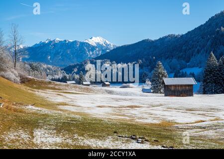 Berglandschaft im Winter, vor Holzhütten, hinter Karwendelgebirge, Bayerisches Oberland, Garmisch-Patenkirchen, Bayern, Deutschland Stockfoto