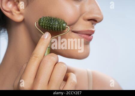 Dame mit einem glücklichen Lächeln, die sich eine Gesichtsmassage gibt Stockfoto