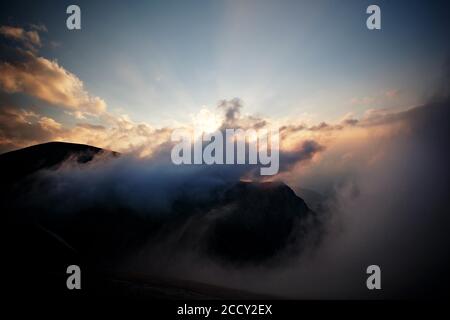 Untergehende Sonne über einer Bergkette, durchschneiden die Wolken, Czerwone Wierchy, Tatra-Gebirge, Tatra-Nationalpark, Polen Stockfoto