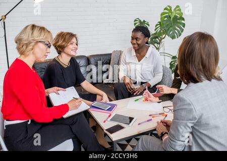 Multirassischen weibliche Mitarbeiter sitzen gemeinsam am Tisch, in Zusammenarbeit. Brainstorming Planung Sitzung Konzept. Stockfoto