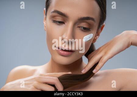 Schöne verträumte kaukasische Dame berührt ihren Pferdeschwanz Stockfoto