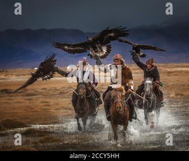 Mongolische Adler Jäger. Drei Kasachen auf dem Pferderücken mit ausgebildeten Adlern. Bayan-Ulgii Provinz, Mongolei Stockfoto