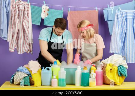Mann und Frau konzentrierten sich auf die Wäsche, Paar mit Händen auf Schüssel mit Schaum. Nahaufnahme Porträt. Isoliert blauen Hintergrund. studio erschossen. Stockfoto