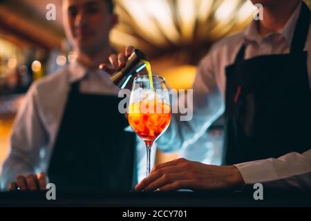 Barkeeper Hand Rühren eines frischen und süßen orange Sommer Cocktail mit einem Löffel auf der Theke. Stockfoto