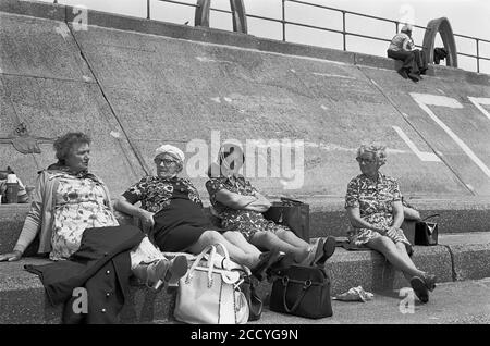 Der heiße Sommer 1976 - Rentner plaudern, während Liebhaber sich am Strand von Aberavon, South Wales, küssen Stockfoto