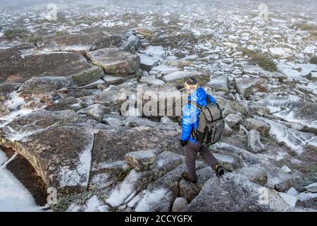 Nicht identifizierter Tourist mit Rucksack den Berg hinunter auf gefroren Steine Stockfoto