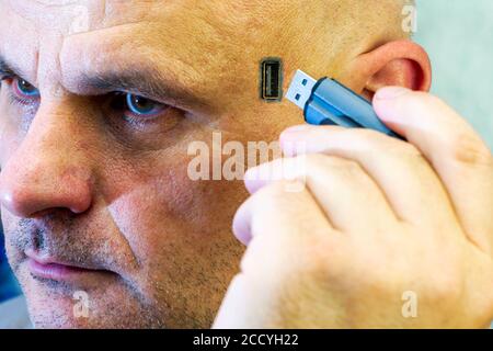Konzept Computerisierung Chippisierung Computerabhängigkeit ein Mann fügt einen Blitz ein Fahren Sie in seinen Kopf ein USB-Anschluss befindet sich auf Seinen Kopf Stockfoto