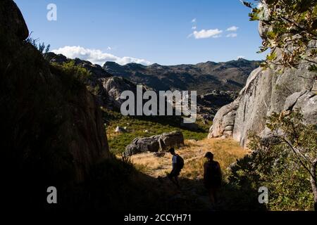 Wanderer im Gegenlicht gehen bergab in einer Berglandschaft auf Ein sonniger Tag Stockfoto