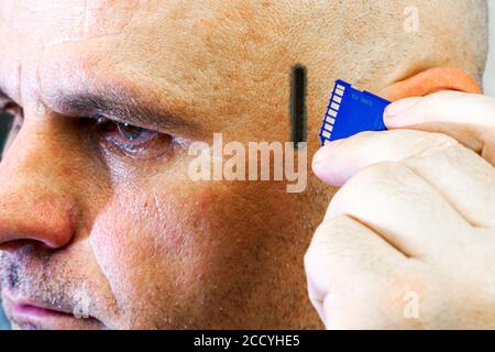 Konzept Computerisierung Chippisierung Computerabhängigkeit ein Mann fügt einen Blitz ein Fahren Sie in seinen Kopf ein USB-Anschluss befindet sich auf Seinen Kopf Stockfoto