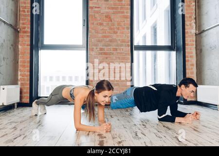 Fleißiges Mädchen und Kerl unter Teilnahme an Fitness-Programm. Frau und Mann tun Übungen für abs Stockfoto