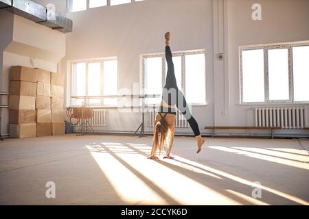 Junge gut geformte Frau Performing Art Gymnastik Element, so dass Handstand in der Gymnastikschule, Spaltsprung in der Luft, Sport und Erfolg conce Stockfoto