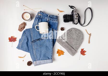 Feminine Kleidung, Kamera und gelbe Blätter auf weißem Tisch Stockfoto