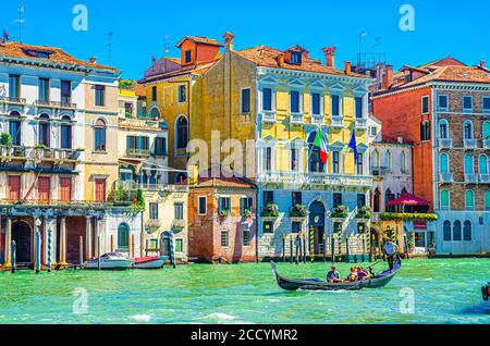 Venedig, Italien, 13. September 2019: Gondoliere und Touristen auf Gondel traditionelle Boot Segeln auf dem Wasser des Canal Grande Wasserstraße mit venezianischer Architektur typischen bunten Gebäuden Hintergrund Stockfoto