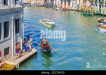 Venedig, Italien, 13. September 2019: Gondoliere und Touristen auf Gondel traditionelle Boot Segeln auf dem Wasser des Canal Grande Wasserstraße mit venezianischer Architektur typischen Gebäuden Hintergrund Stockfoto