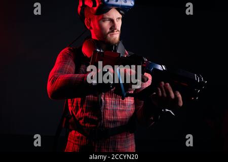 Porträt des Mannes im Studio, schwarzer Hintergrund, ultraviolette Strahlen auf den Menschen reflektiert. Hält Spezialwaffe Stockfoto