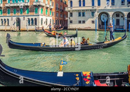Venedig, Italien, 13. September 2019: Gondoliere und Touristen auf Gondel traditionelle Boot Segeln auf dem Wasser des Canal Grande Wasserstraße mit venezianischer Architektur typischen bunten Gebäuden Hintergrund Stockfoto