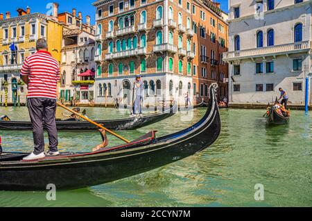 Venedig, Italien, 13. September 2019: Gondoliere und Touristen auf Gondel traditionelle Boot Segeln auf dem Wasser des Canal Grande Wasserstraße mit venezianischer Architektur typischen bunten Gebäuden Hintergrund Stockfoto