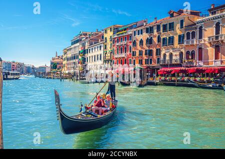 Venedig, Italien, 13. September 2019: Gondoliere und Touristen auf Gondel traditionelle Boot Segeln auf dem Wasser des Canal Grande Wasserstraße mit venezianischer Architektur typischen bunten Gebäuden Hintergrund Stockfoto