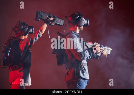 Kaukasischen Mann und Frau stehen halten virtuelle Waffe und tragen Brille, Innovation Zukunft. Stockfoto