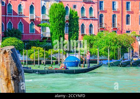 Venedig, Italien, 13. September 2019: Gondoliere und Touristen auf Gondel traditionelle Boot Segeln auf dem Wasser des Canal Grande Wasserstraße mit venezianischer Architektur typischen bunten Gebäuden Hintergrund Stockfoto