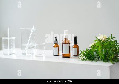 Heller kosmetischer Hintergrund. Fläschchen, Laborflaschen aus Glas auf dem Tisch. Naturkosmetik-Konzept. Stockfoto