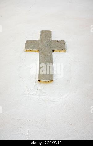 Ein altes religiöses Marmorkreuz, eingebettet in eine weiße Wand. Stockfoto