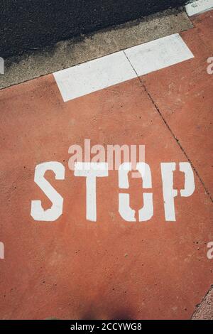 Das Wort Stop in weißen Großbuchstaben auf einem roten Boden gemalt. Stockfoto