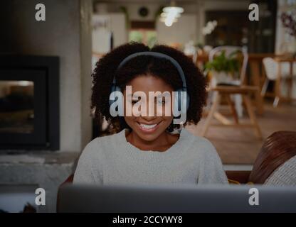 Portrait der fröhlichen jungen Frau entspannend und Musik hören Verwenden von Kopfhörern mit Laptop Stockfoto