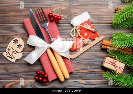 Blick von oben auf die Weihnachtsdekorationen auf Holz- Hintergrund. Nahaufnahme von Gabel und Messer auf Serviette mit Schleife gebunden. Neues Jahr Muster Konzept. Stockfoto