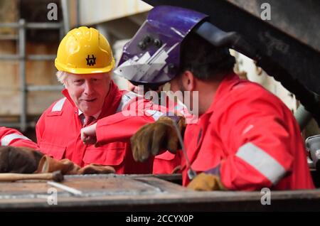 Premierminister Boris Johnson Ellenbogen stößt einen Schweißer während seines Besuchs auf Appledore Shipyard in Devon, die von InfraStrata, die Firma, die auch Belfast Harland & Wolff (H&W) besitzt, in einem £7 Millionen-Deal gekauft wurde. Stockfoto