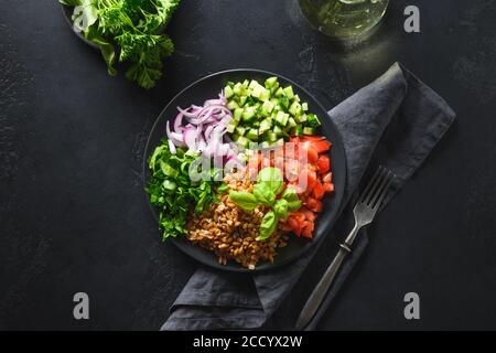 Gekochter Vollkorngetreide Dinkelsalat mit saisonalem Gemüse in einer Schüssel auf braunem Hintergrund. Stockfoto