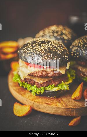 Schwarze doppelte Burger mit Käse. Cheeseburger aus Japan mit schwarzem Brötchen auf dunklem Hintergrund Stockfoto