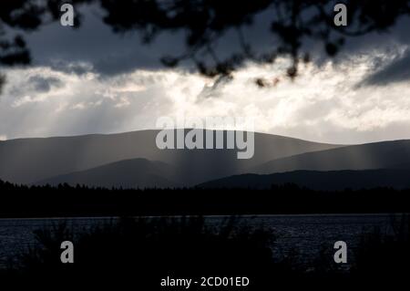 Silouhette einer Bergkette hinter einem See am Abend. Schottisches Hochland, Loch Morlich, Glen More, Cairngorms National Park Stockfoto