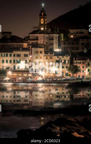 Waterfront in Bogliasco in der Nacht mit Lichtreflexen auf dem ruhigen Wasser des Mittelmeers an der Küste von Ligurien, Italien, ein beliebter Ferienort Stockfoto