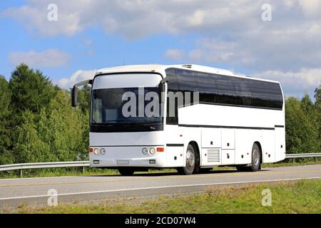 Weißer Reisebus fährt entlang der Autobahn an einem schönen Tag des Sommers, blauer Himmel und Wolken Hintergrund. Stockfoto