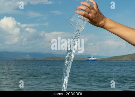 Sauberes Wasser fließt aus einem Plastikbecher. Stockfoto