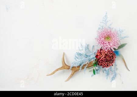 Geweih mit Blumen auf weißem Marmor Hintergrund mit leeren Raum für Text dekoriert. Draufsicht, flach liegend. Stockfoto