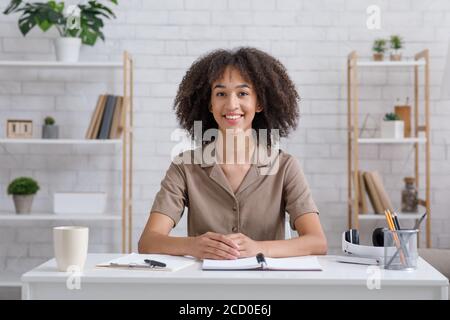 Fernlernsprache. Lächelnder Lehrer sitzt am Tisch, schaut auf die Kamera und kommuniziert mit den Schülern Stockfoto